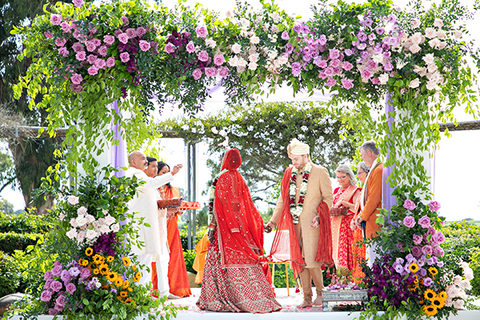 Three women in colorful outfits sitting on a bed of flowers.