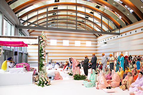 Three women in colorful outfits sitting on a bed of flowers.
