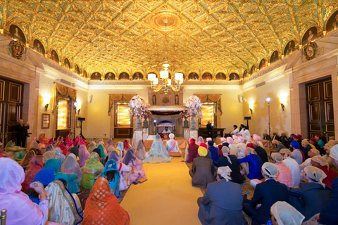 Three women in colorful outfits sitting on a bed of flowers.