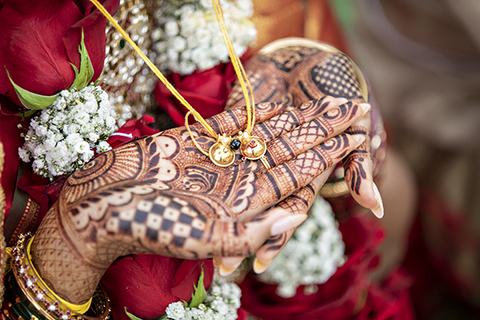 Three women in colorful outfits sitting on a bed of flowers.