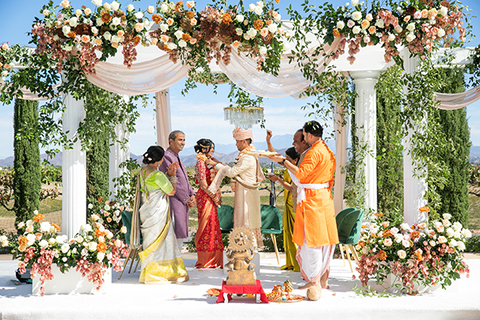 Three women in colorful outfits sitting on a bed of flowers.