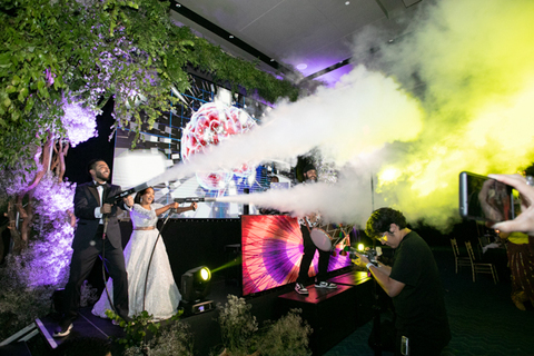 Three women in colorful outfits sitting on a bed of flowers.