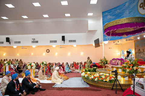 Three women in colorful outfits sitting on a bed of flowers.