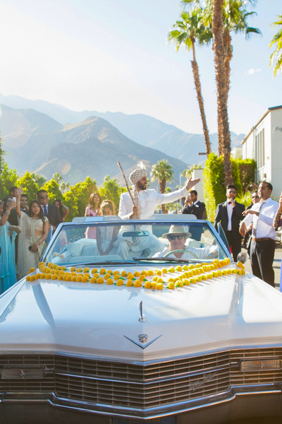 A man in white shirt riding on the back of a car.