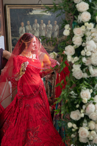 A woman in red dress standing next to flowers.