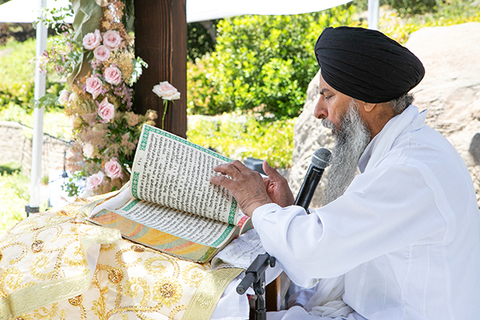 Three women in colorful outfits sitting on a bed of flowers.