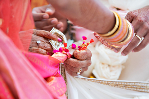 Three women in colorful outfits sitting on a bed of flowers.