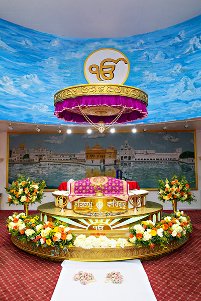 Three women in colorful outfits sitting on a bed of flowers.